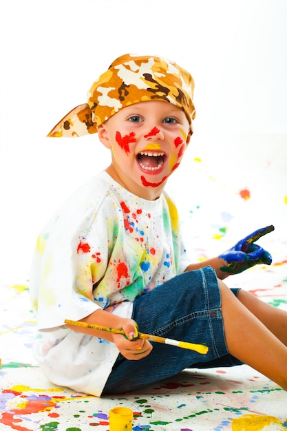 Photo little boy stained in paint draws