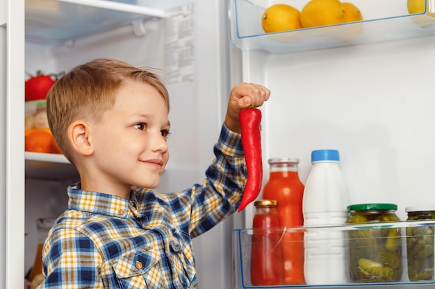 オープン冷蔵庫の近くに立っている小さな男の子