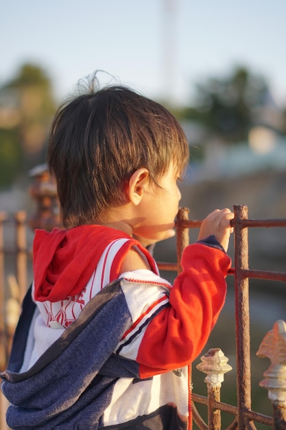 写真 手すりの上に立って前を見つめる小さな男の子