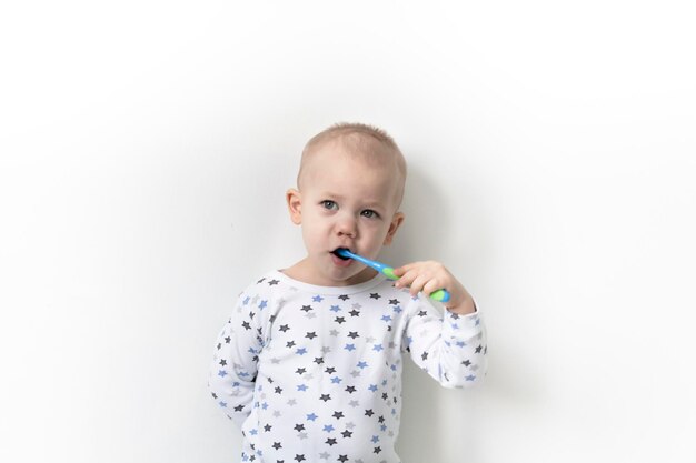 A little boy stands against dressed in a Tshirt stars brushes his teeth and takes care of his mouth