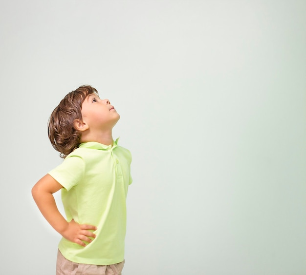 little boy stands in profile and looks up