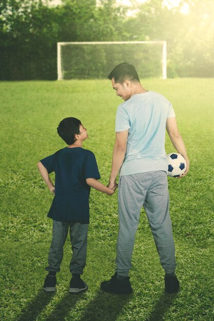 サッカー場で父親と一緒に立っている小さな男の子