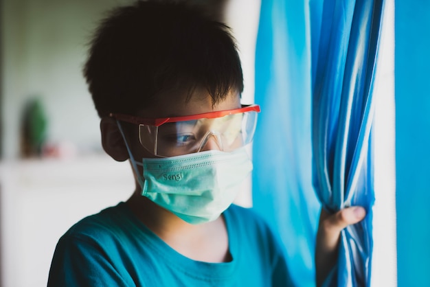 Little boy stay at home quarantine time looking outside from the window