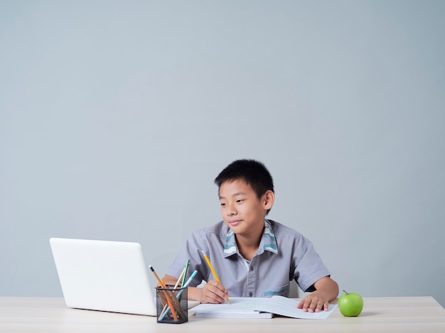 Little boy studying online with laptop. Distance learning during COVID-19 pandemic