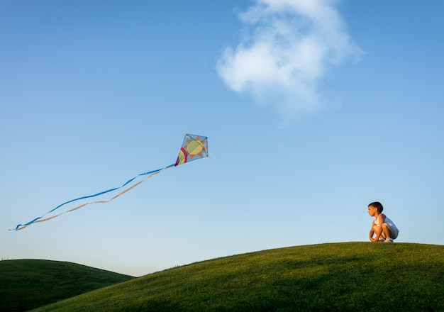 Little boy on summer vacation having fun and happy time flying kite on the sea beach