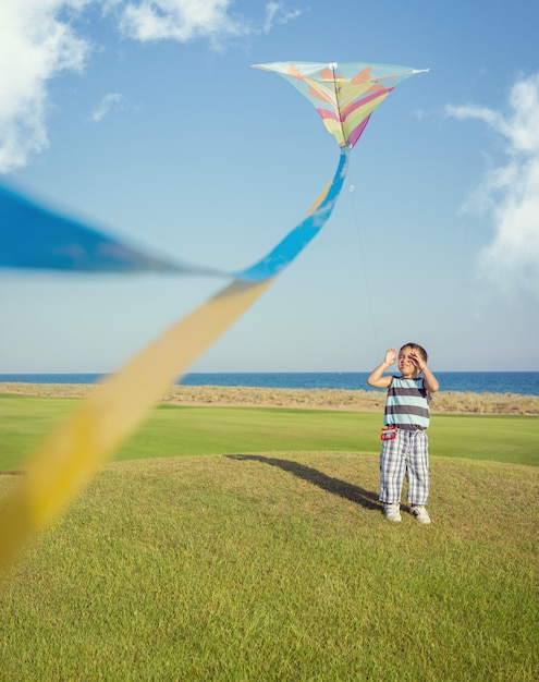 Маленький мальчик на летние каникулы, с удовольствием и счастливым время полета воздушных змеев на морском пляже