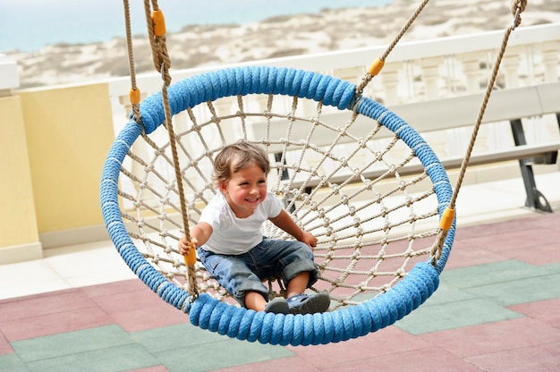 Little boy swinging in the beach view