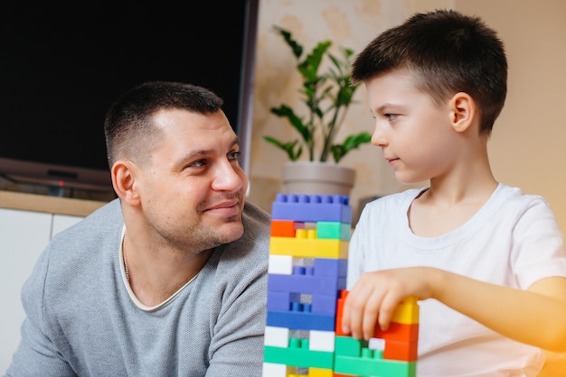 A little boy together with his father is played by a constructor and builds a house. Construction of a family home.