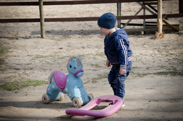 小さな男の子と遊び場でおもちゃの馬