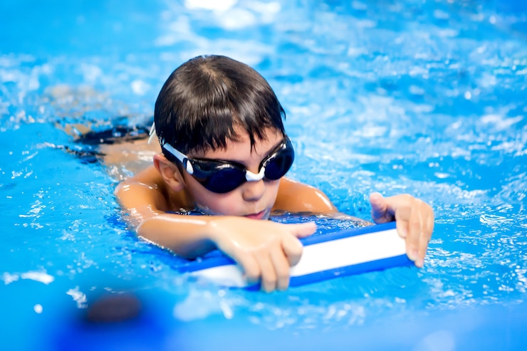 Photo little boy trains to swim in the pool