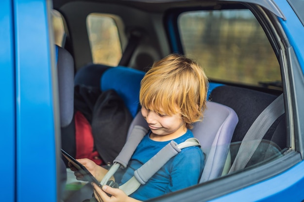 Foto ragazzino che viaggia sul sedile posteriore di un'auto utilizzando il touch pad per intrattenersi durante il viaggio