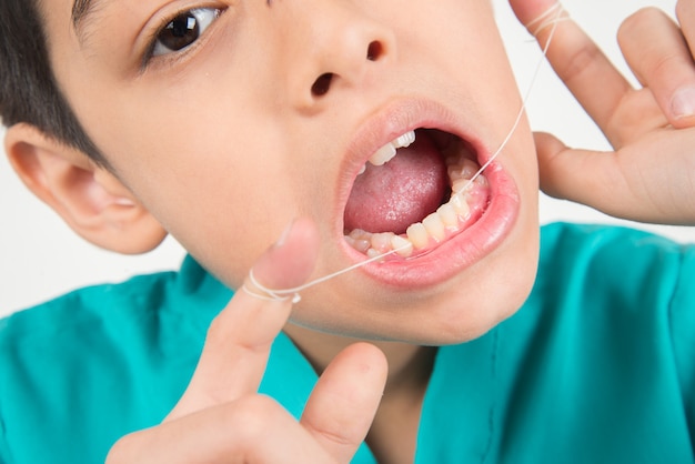 치실을 사용하여 치아를 청소하는 어린 소년