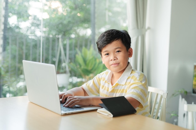 Маленький мальчик с помощью ноутбука изучает математику во время онлайн-урока дома
