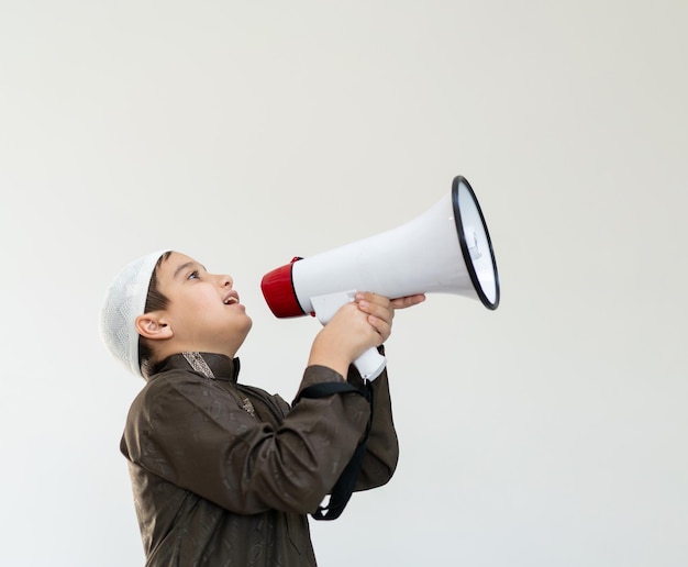 Little boy using megaphone shouting on blue background high quality photo