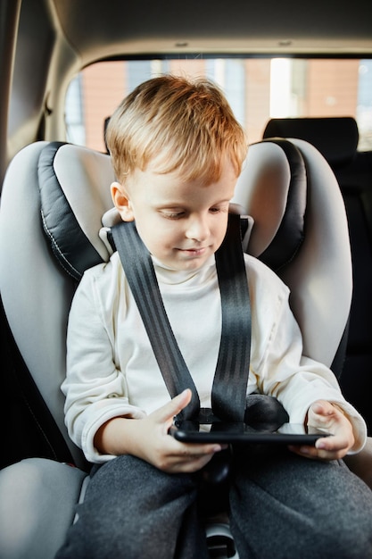 Photo little boy using smartphone in car