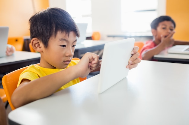 Photo little boy using tablet pc in classroom