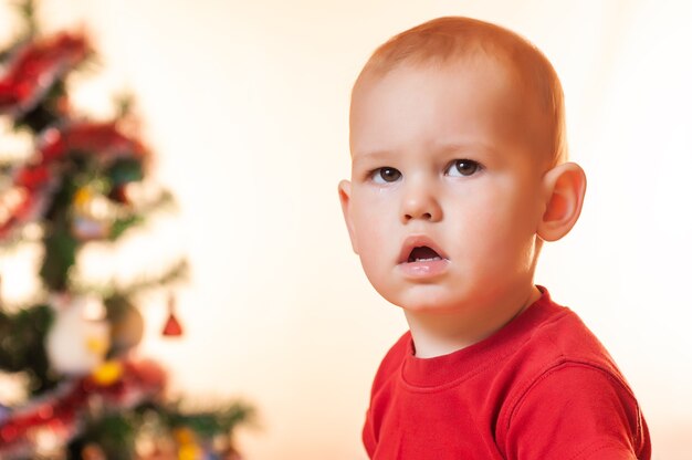 A little boy waiting for gifts from Santa Claus is sad and crying near the New Year tree.