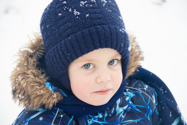 Little boy on a walk in the Park in winter. Winter park. A boy in winter overalls. Snow in the Park .