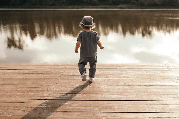 Photo little boy walking alone towards lake