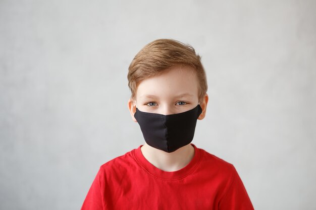 Маленький мальчик в маске от вируса короны covid-19, 2019-nCov. Ребенок в хирургической повязке или респираторе во время коронавируса