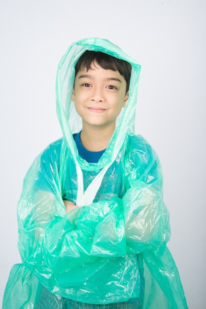 Little boy wearing rain coat on white wall