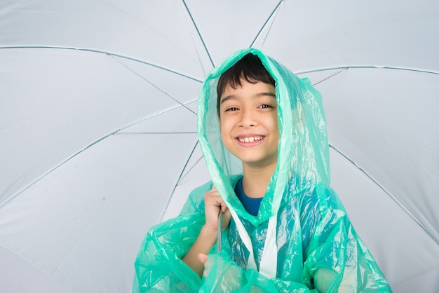 Little boy wearing rain coat on white wall