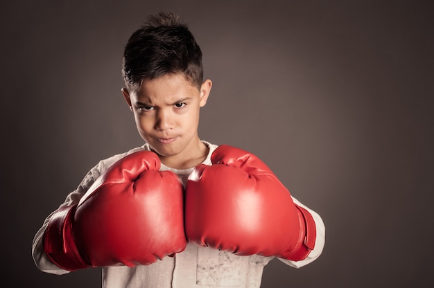 Little boy wearing red boxing gloves