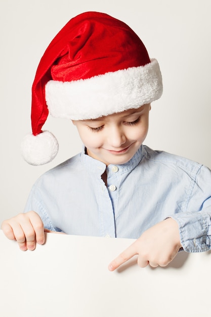 Little Boy Wearing Santa Hat Point the Finger at White Banner