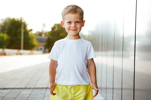 白いTシャツを着た小さな男の子。ロゴやデザインのためのスペース。印刷用のモックアップ