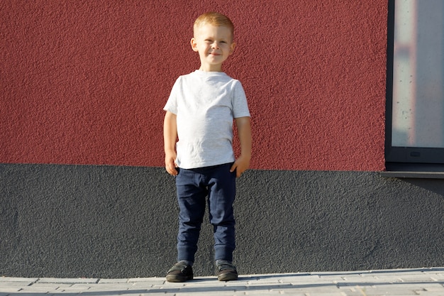 白いTシャツを着た小さな男の子。ロゴやデザインのためのスペース。印刷用のモックアップ