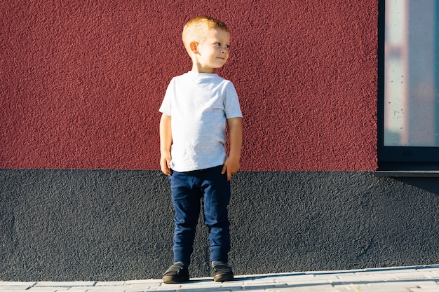 白いTシャツを着た小さな男の子。ロゴやデザインのためのスペース。印刷用のモックアップ