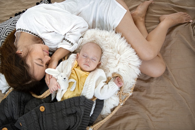 Little boy in a wicker cradle with a toy on the background of a blanket top view.