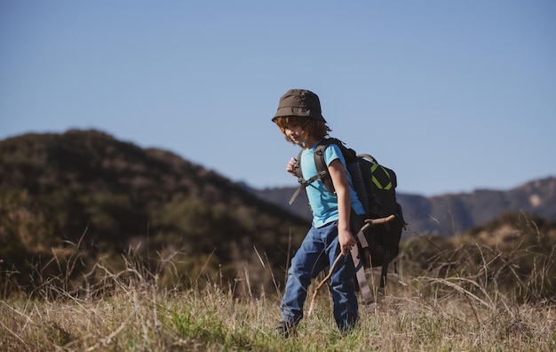 Little boy with backpack hiking in scenic mountains boy local tourist goes on a local hike