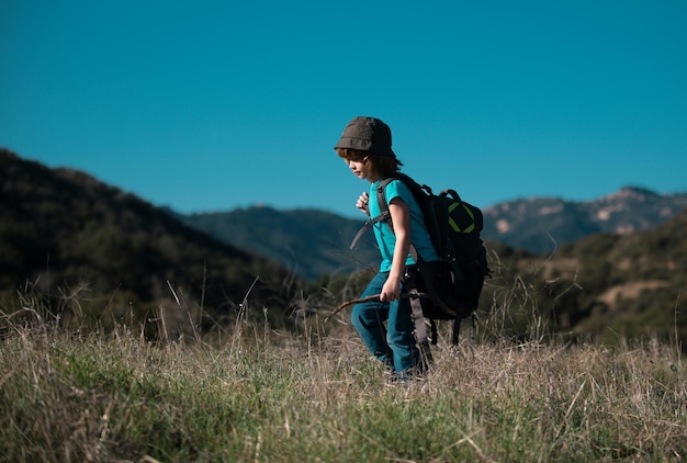 Little boy with backpack hiking in scenic mountains boy local tourist goes on a local hike