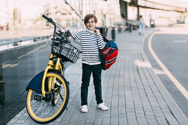 Little boy with a backpack near a bike