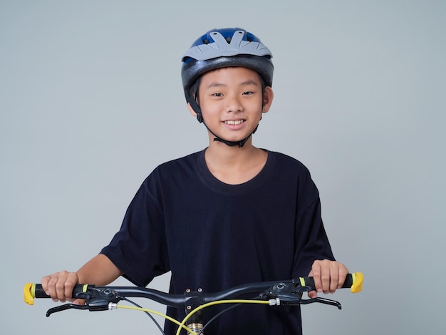 Маленький мальчик с велосипедом на светлом фоне