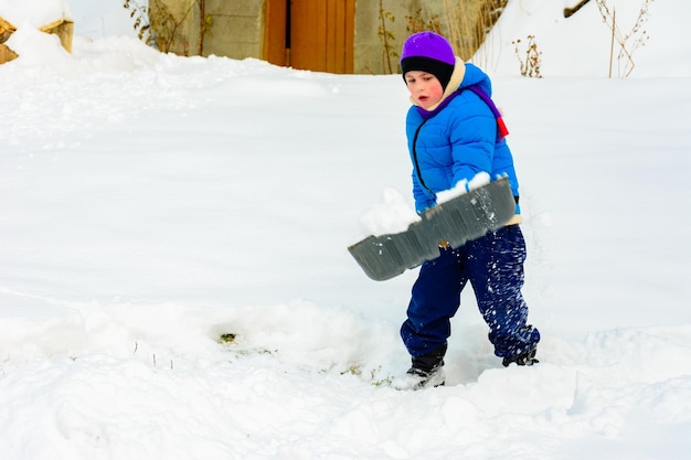 Il ragazzino con la grande pala rimuove la neve dopo una tempesta di neve