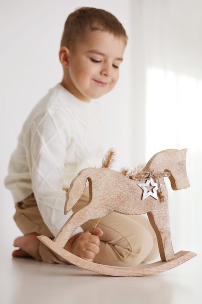 白い背景の上のクリスマスのアクセサリーを持つ小さな男の子。幸せな子供、クリスマスのお祝い、クリスマスの時間。