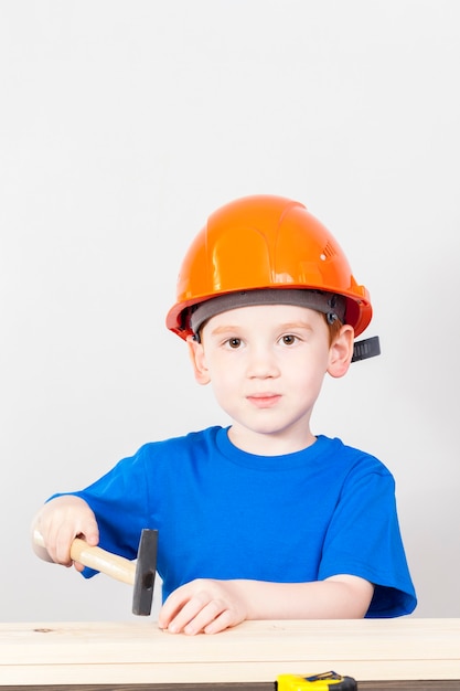 Little boy with a hammer and other construction tools during work education lessons