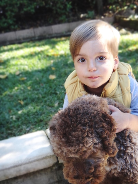 Foto ragazzino con il suo cane seduto in giardino
