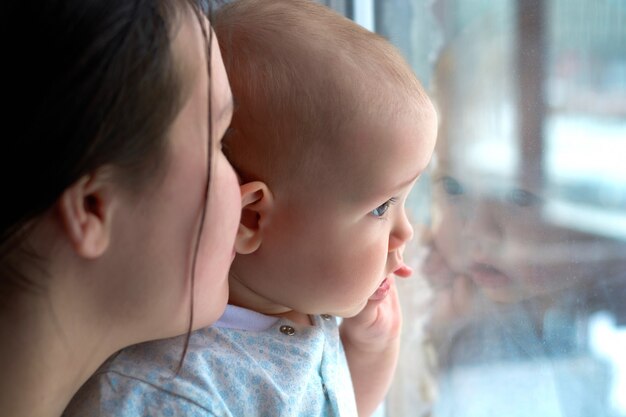 A little boy with his mother looks out the window.