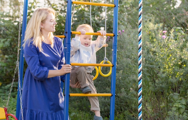 Little boy with his mother  on playground on summer day