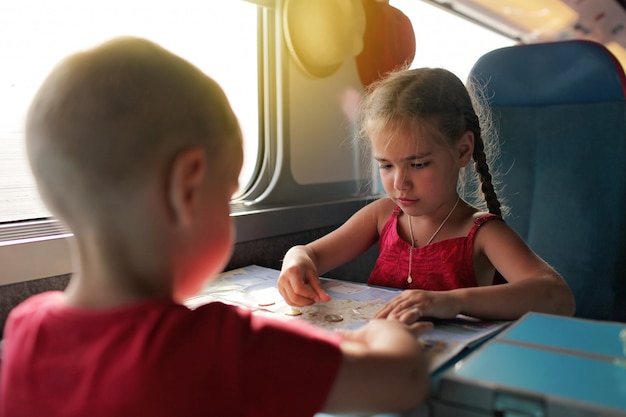 Photo little boy with his sister discussing their economy vacation during travelling by train