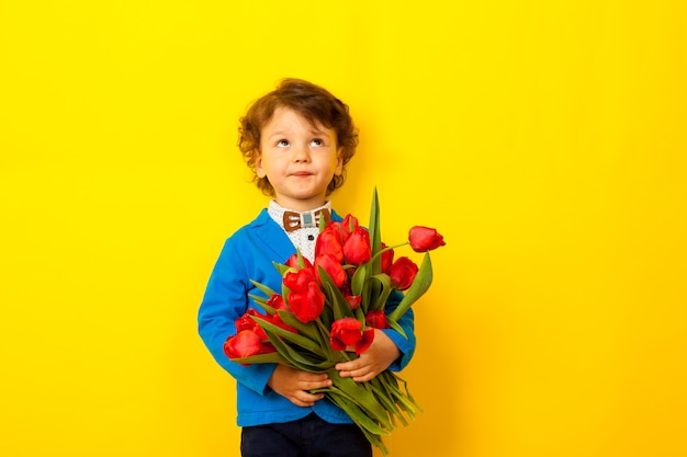 A little boy with a huge bouquet of flowers, in festive clothes