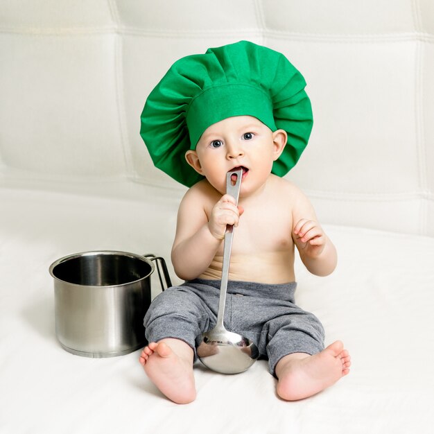 Ragazzino con mestolo in metallo e cappello da cuoco