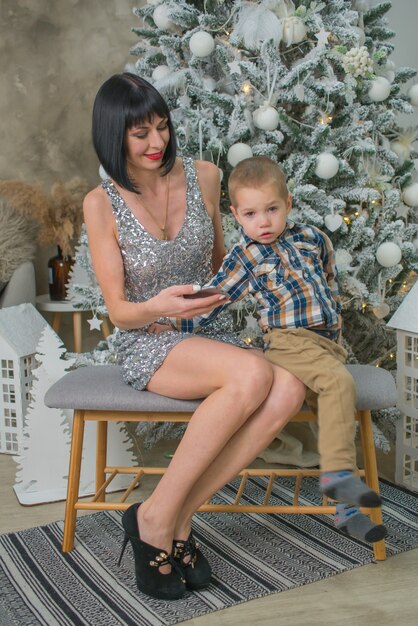 little boy with mom at home near the christmas tree with gifts in christmas