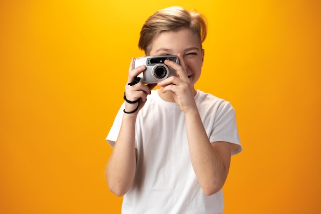 Little boy with an old camera on a yellow background