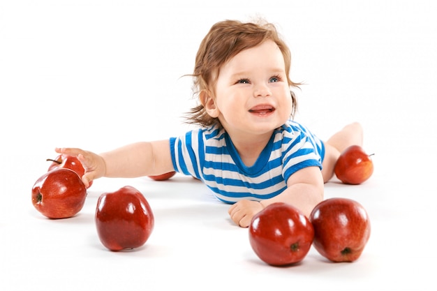 A little boy with a pile of apples