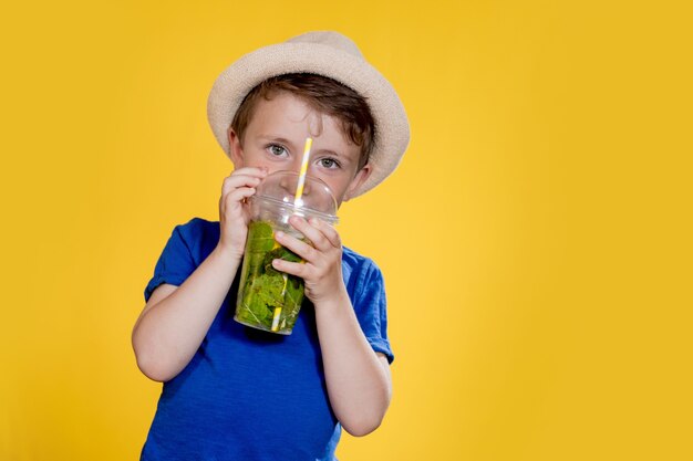 新鮮なレモネードのプラスチックカップを持つ小さな男の子