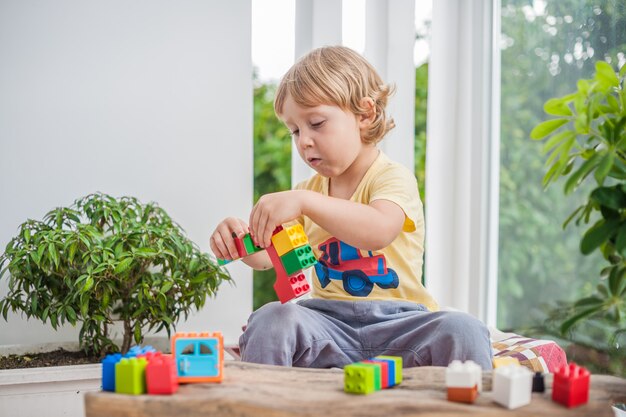 カラフルなプラスチック製のブロックを屋内で遊ぶ少年